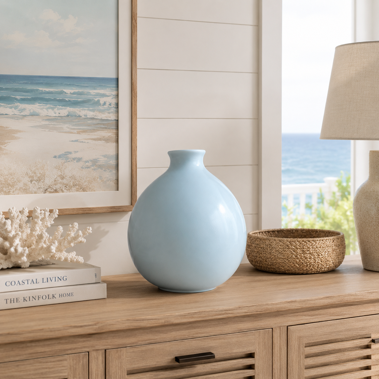 Light blue vase on a wooden console table with coastal decor elements.